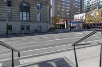 a metal handrail on the side of an empty street next to buildings and a bus