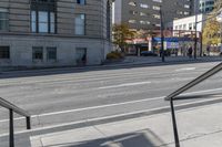 a metal handrail on the side of an empty street next to buildings and a bus