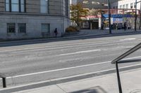 a metal handrail on the side of an empty street next to buildings and a bus