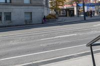 a metal handrail on the side of an empty street next to buildings and a bus