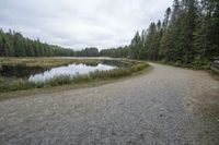 the gravel road to the lake next to it is empty with no vehicles on it