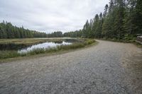 the gravel road to the lake next to it is empty with no vehicles on it