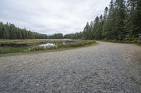 the gravel road to the lake next to it is empty with no vehicles on it