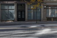 a building on the street that has two windows with no cars parked on it and there are yellow lights