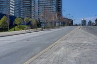 a wide empty road that leads down to buildings on both sides of it and in the distance there is an orange stop sign