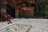 a patio in front of the garage with large brick pathway and water feature on the concrete