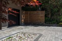 a patio in front of the garage with large brick pathway and water feature on the concrete