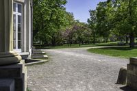 a pathway leads to a park with trees in the background and benches on the far side