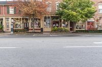 an empty city street with buildings in the background and lots of trees on either side