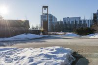 an empty parking lot is pictured in the sun with some snow on the ground and trees