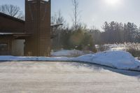 a snow covered hillside with a building in the background and sun shining on top of a house