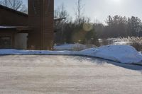 a snow covered hillside with a building in the background and sun shining on top of a house