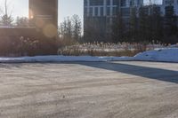 a snow covered hillside with a building in the background and sun shining on top of a house