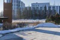 a snow covered hillside with a building in the background and sun shining on top of a house