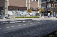 a woman on a bike is waiting to cross the street at an intersection, in front of stores