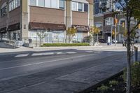 a woman on a bike is waiting to cross the street at an intersection, in front of stores