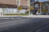 a woman on a bike is waiting to cross the street at an intersection, in front of stores