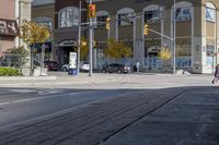 a woman on a bike is waiting to cross the street at an intersection, in front of stores