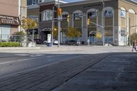 a woman on a bike is waiting to cross the street at an intersection, in front of stores