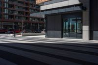 a brick building next to an empty walkway in front of a sidewalk with cars driving by