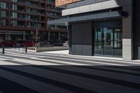 a brick building next to an empty walkway in front of a sidewalk with cars driving by