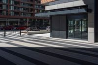 a brick building next to an empty walkway in front of a sidewalk with cars driving by