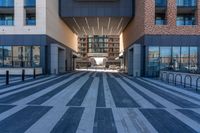 two buildings with windows have large reflective glass windows that overlook over the courtyard, and a street that has bicycle racks