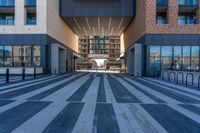 two buildings with windows have large reflective glass windows that overlook over the courtyard, and a street that has bicycle racks