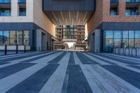 two buildings with windows have large reflective glass windows that overlook over the courtyard, and a street that has bicycle racks