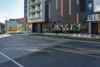 a large building is next to an open street with a car driving down the middle