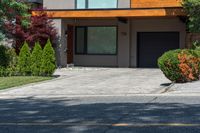 a dog is laying in the driveway of a house with bushes and trees outside of it