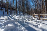 snow covered path with wooden fence on the side of a hill at winter time, with sun streaming through