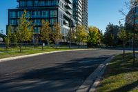 a city street lined with tall buildings on the sides of it and green grass on both side