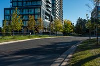 a city street lined with tall buildings on the sides of it and green grass on both side