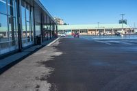 the empty parking lot of a store, with a reflection in the windows of it