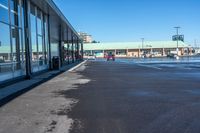 the empty parking lot of a store, with a reflection in the windows of it