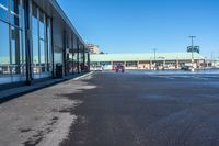 the empty parking lot of a store, with a reflection in the windows of it