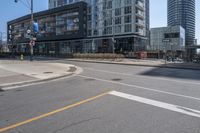 there is a bike going down the street in front of a large building, while an empty parking lot stands at the curb