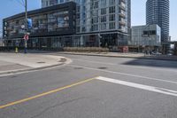 there is a bike going down the street in front of a large building, while an empty parking lot stands at the curb