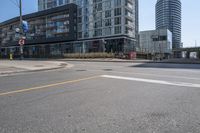 there is a bike going down the street in front of a large building, while an empty parking lot stands at the curb