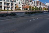 the tall buildings are surrounded by greenery on this residential street side lined with apartment buildings