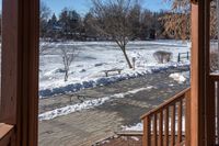 a small wooden walkway leading to a covered porch in the winter with snow on it