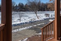 a small wooden walkway leading to a covered porch in the winter with snow on it