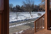 a small wooden walkway leading to a covered porch in the winter with snow on it