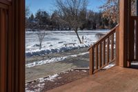 a small wooden walkway leading to a covered porch in the winter with snow on it