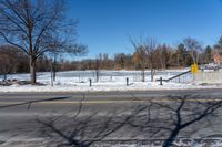 there is snow and a small park on the side of a road by it's side