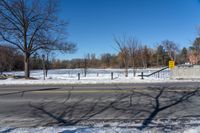 there is snow and a small park on the side of a road by it's side