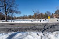 there is snow and a small park on the side of a road by it's side