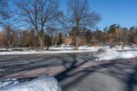 a street in a snow covered area with trees, a small building and a fence