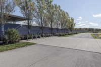 a large parking lot with lots of trees around it and a sidewalk in front of the building